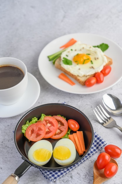 無料Photo 木のスプーンとコーヒーカップにトマトと鍋にゆで卵、ニンジン、トマト。