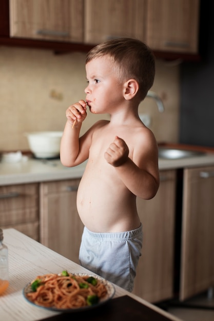 Foto gratuita ragazzo che mangia spaghetti in cucina