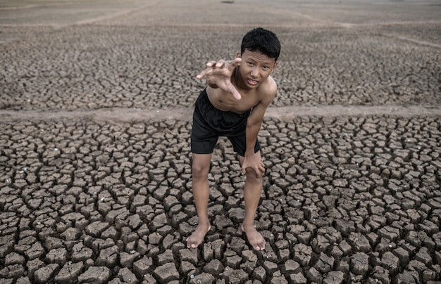 Free photo the boy stood bent on his knees and made a mark to ask for rain, global warming and water crisis.