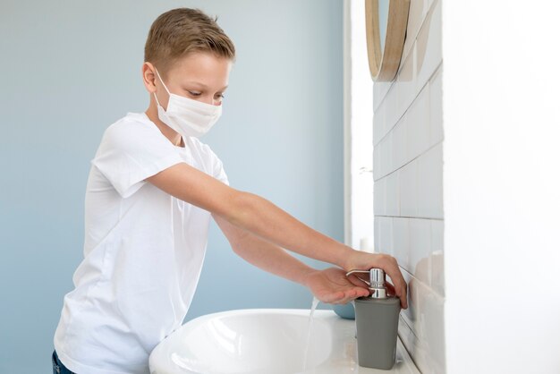 Boy wearing medical mask and washing his hands