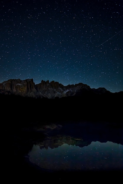 Free photo breathtaking scenery of the starry sky and rocky cliffs reflecting on the lake at night time