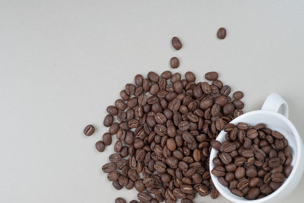 Free photo bunch of coffee beans out of white mug