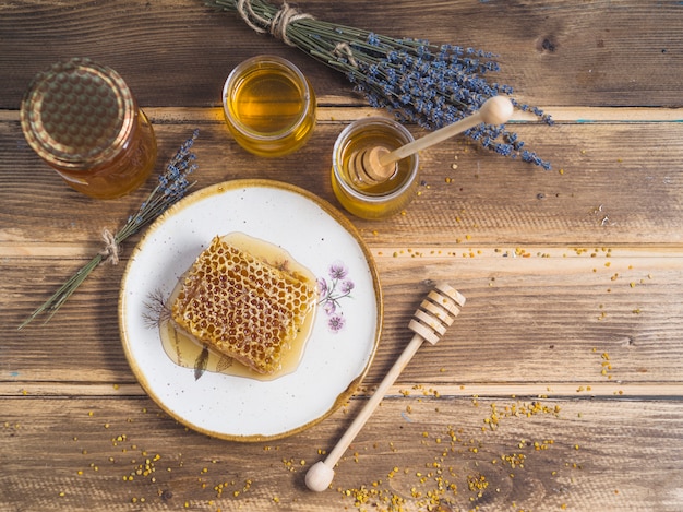 Free photo bunch of lavender; honey pot; and honeycomb piece on plate over the table