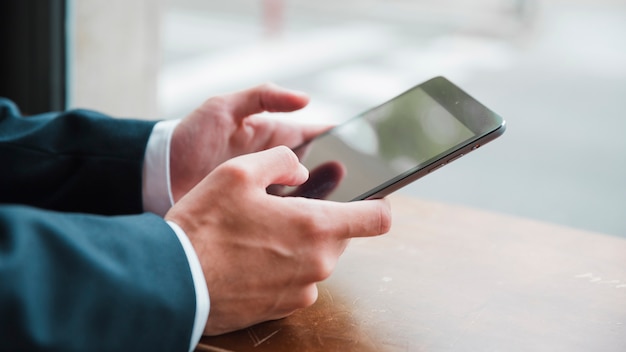 Free Photo businessman's hand using smart phone in cafe