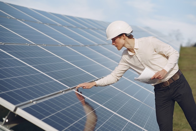 Free photo businessman in a white helmet near solar battery