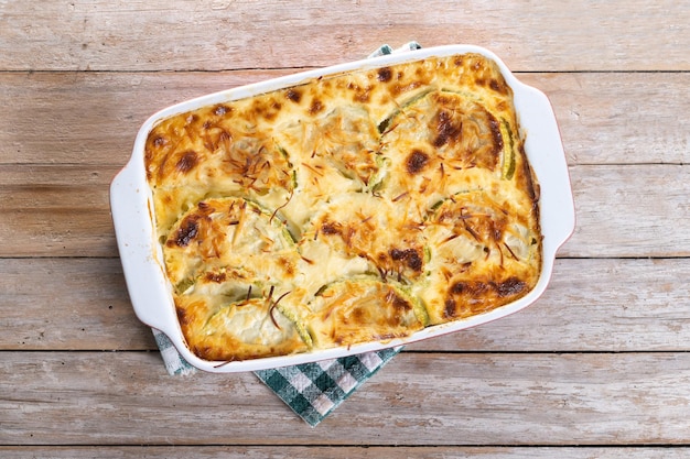 Foto gratuita casserola con formaggio e zucchine grattinate su un tavolo di legno