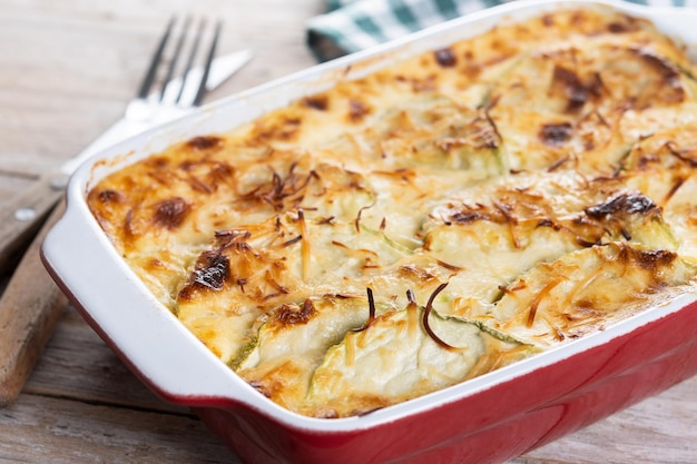 Foto gratuita casserola con formaggio e zucchine grattinate su un tavolo di legno