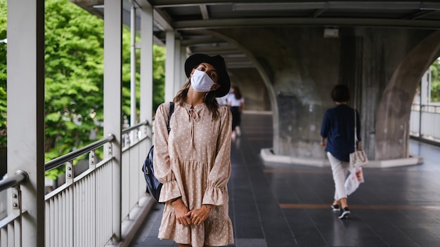 Free photo caucasian woman walking on subway crossing in medical face mask while pandemia in bangkok city.
