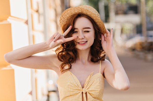 Free Photo charming white woman in vintage dress expressing happiness in summer day. outdoor photo of fashionable ginger lady in hat laughing on city.