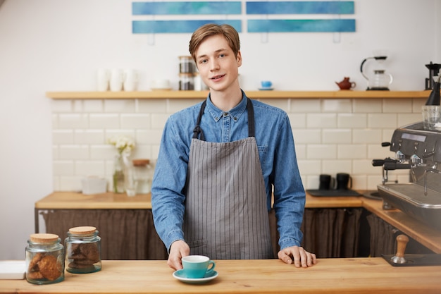 Free photo cheerful barista at bar counter. giving costumer his ordered coffe.