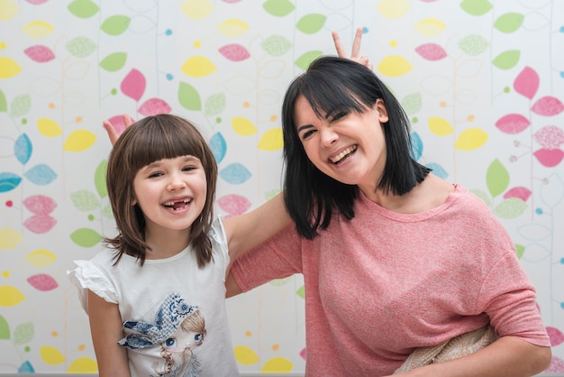 Free photo cheerful daughter and mother making horns with fingers