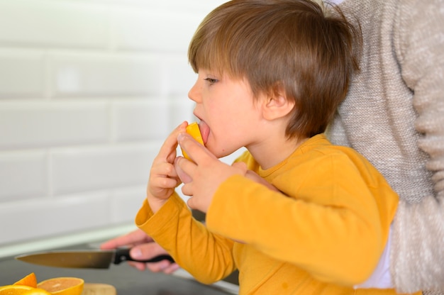 Foto gratuita bambino che mangia un'arancia