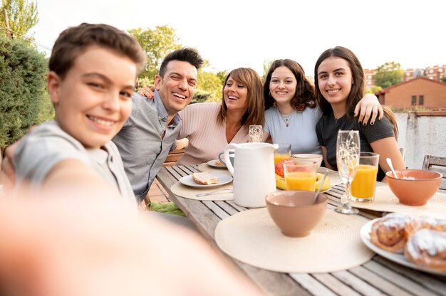 Child taking selfie of family having lunch outdoors together