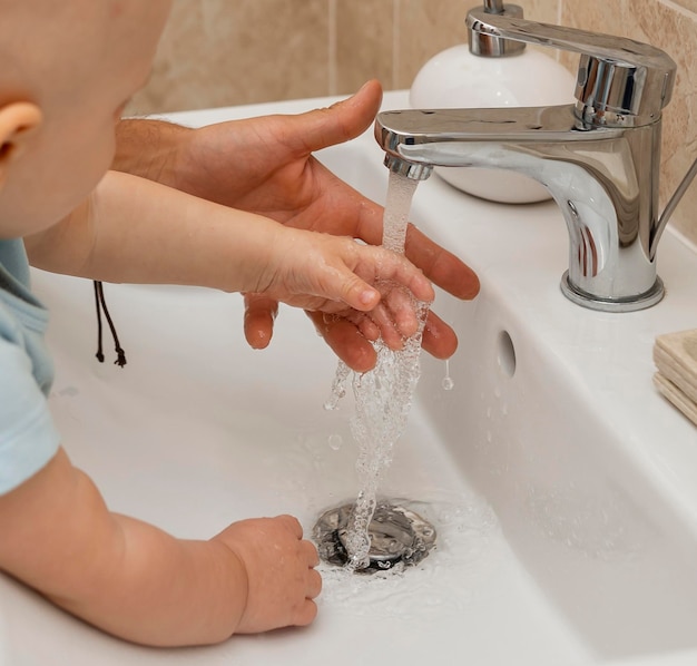 Free photo child washing their hands with the help of parents