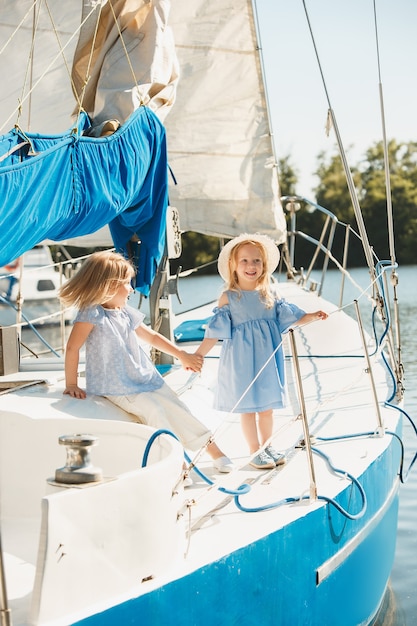 Foto gratuita i bambini a bordo di uno yacht da mare. le ragazze adolescenti o bambine all'aperto. vestiti colorati. concetti di moda per bambini, estate soleggiata, fiume e vacanze.