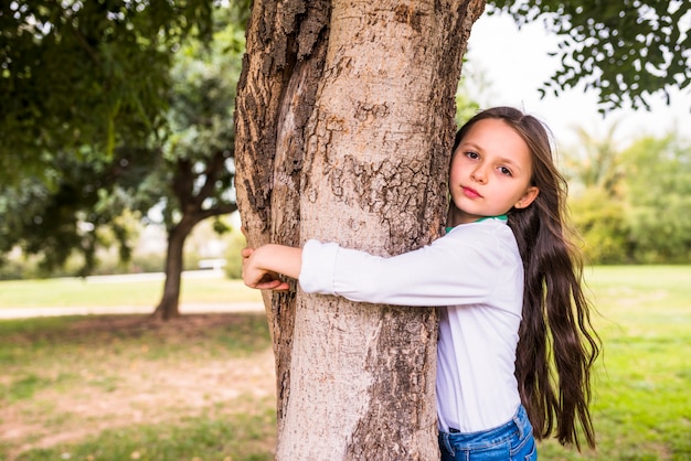 Free photo close-up of a adorable girl hugging tree trunk
