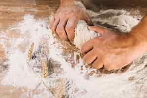 Foto gratuita primo piano della mano di impastare della mano del baker sulla tavola di legno