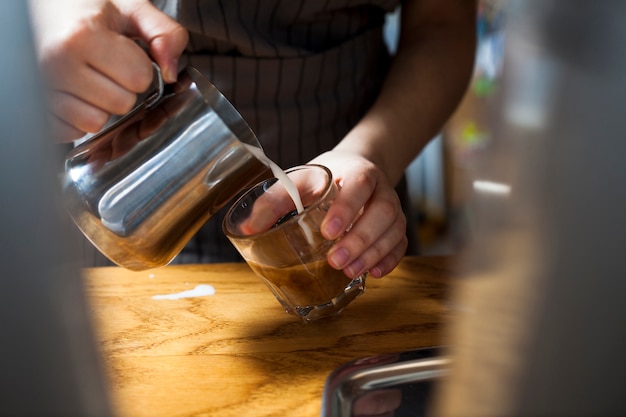 Free photo close-up of barista hand preparing latte coffee over wooden table