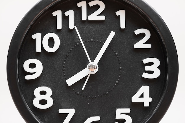 Close-up of a black wall clock face on white background