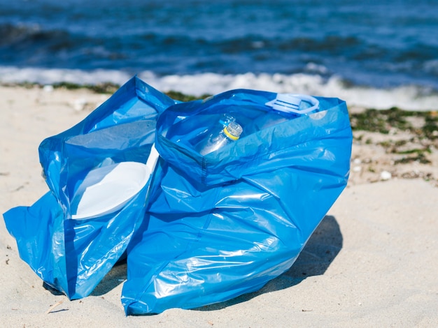 Free Photo close-up of blue garbage bag on sand at beach