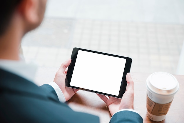 Free photo close-up of a businessman looking at digital tablet with white screen display in caf�