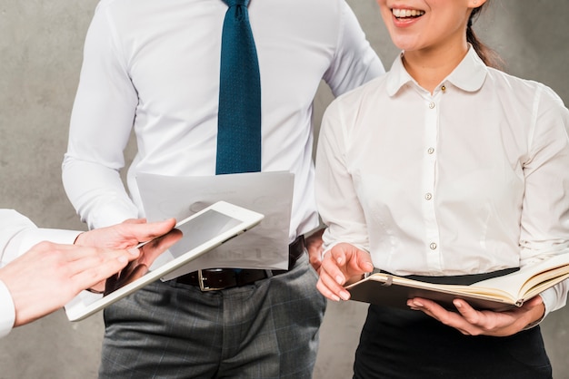 Free photo close-up of businesspeople working together against grey wall