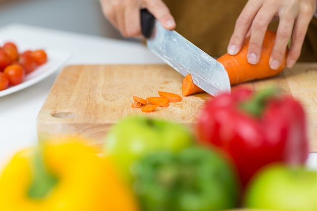 Free photo close-up of female hands cutting carrot on board