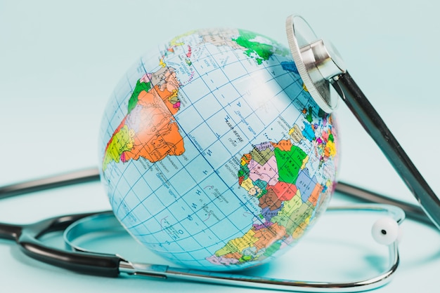 Free photo close-up of globe with stethoscope against blue backdrop