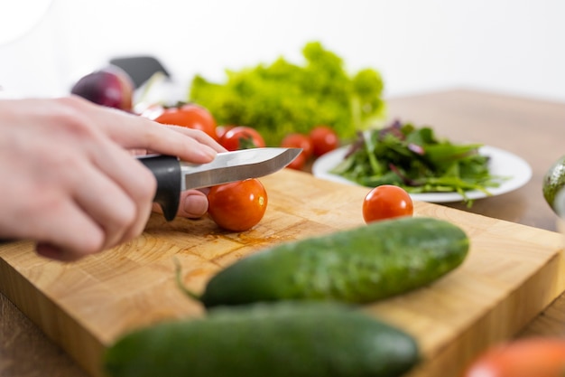 Free photo close up hand cutting tomato with knife