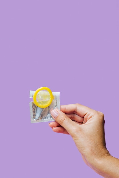 Free photo close-up hand holding yellow condom