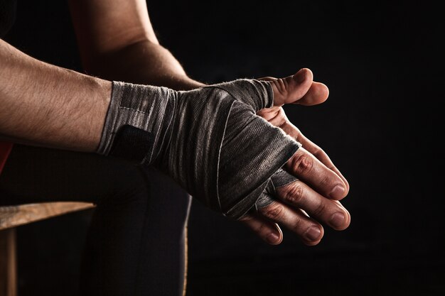 Close-up hand with bandage of muscular man training kickboxing  on black