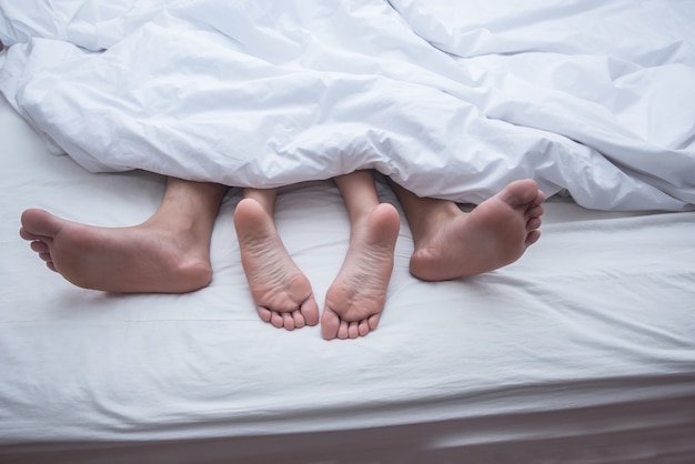 Free photo close up legs of couple in bed