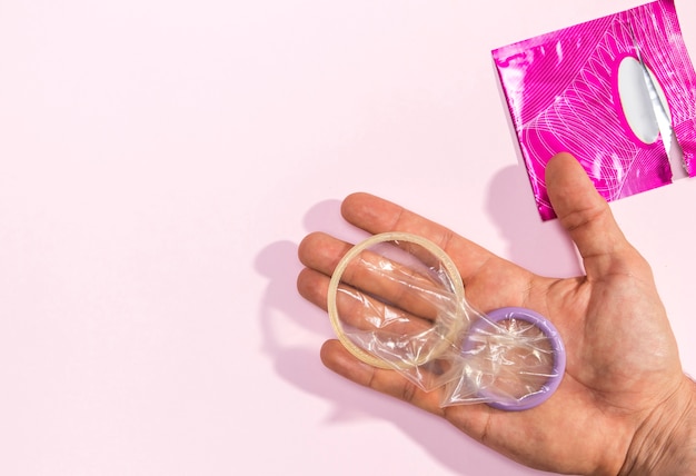 Free photo close-up man holding unwrapped condoms