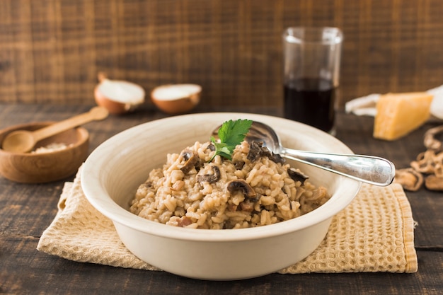 Foto gratuita close-up di risotto ai funghi in una ciotola bianca con un cucchiaio sul tovagliolo sul tavolo