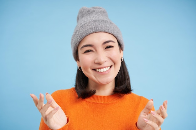 Free photo close up portrait of happy smiling asian woman shows open hands pointing looking friendly standing o