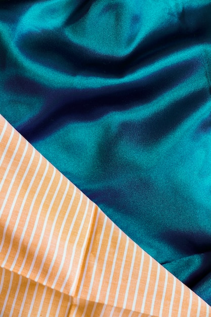 Close-up of silky green textile and orange stripes pattern fabric material