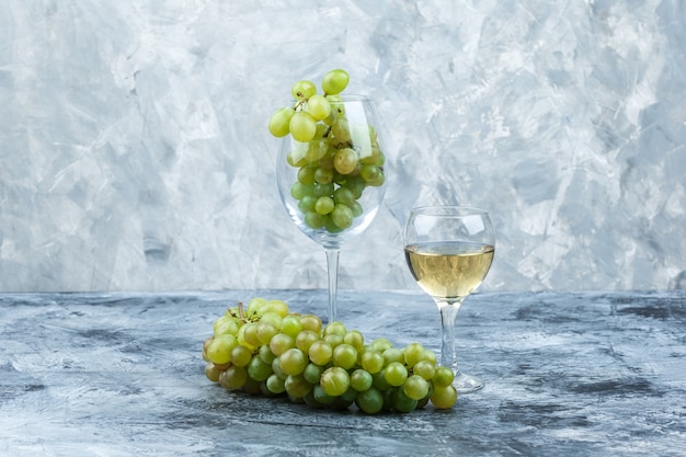 Free photo close-up white grapes, glass of whisky on dark and light blue marble background. horizontal