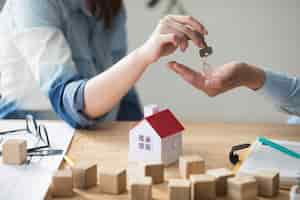 Free photo close-up of woman's hand giving house key to man over wooden table