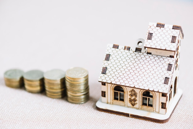 Close-up wooden house near stacks of coins