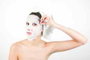 Free photo close-up of young woman pulling white mask from face