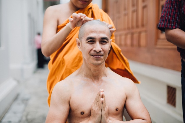 Free Photo closeup image of a handsome asian man is shaving hair by head of man who is ordained in buddhism