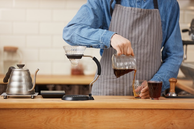 Free photo closeup of male barista hands pouring alternative coffee from chemex.