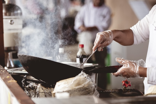 Foto gratuita colpo del primo piano di uno chef che cucina con uno sfondo sfocato