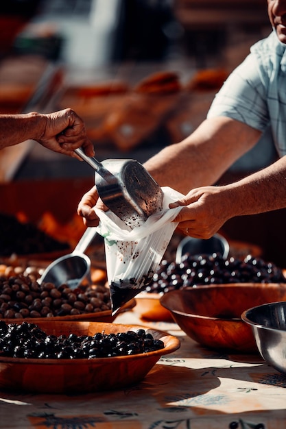 Free photo closeup shot of a customer buying olive and taking it in a plastic case from the seller