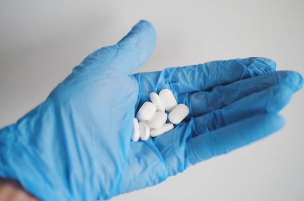 Free photo closeup shot of a person's hands wearing blue gloves and holding white pills