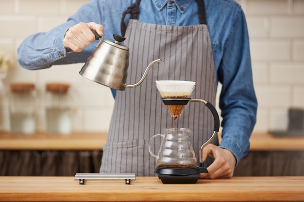 Free photo coffee brewing gadgets. male bartender brewing pouron coffee at bar.