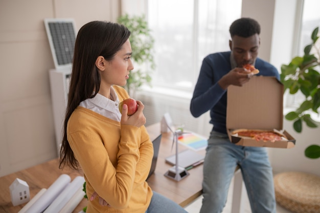 Free photo colleagues at work eating pizza