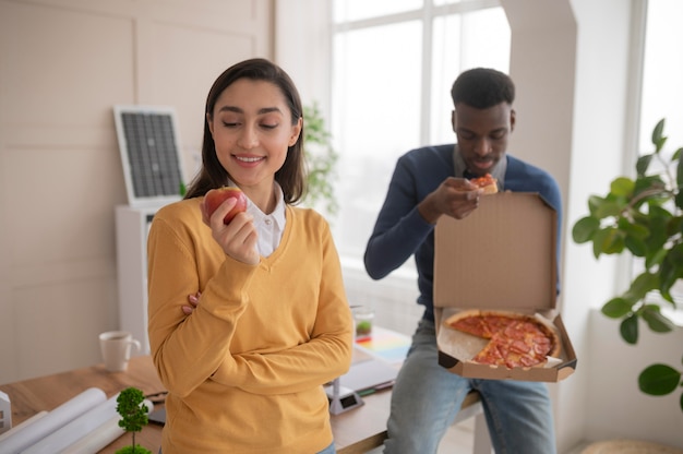 Free photo colleagues at work eating pizza