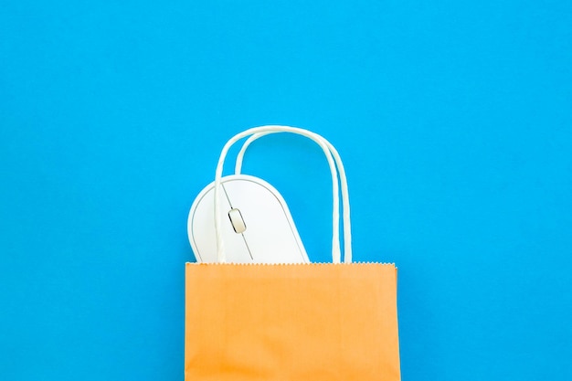 Free photo computer mouse and paper bag on a blue background top view