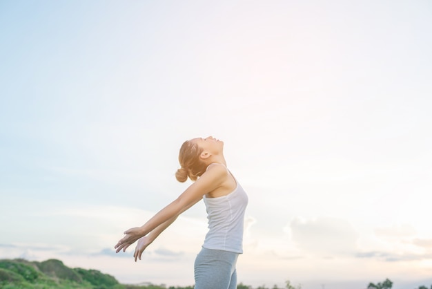 Free photo concentrated woman stretching her arms with sky background